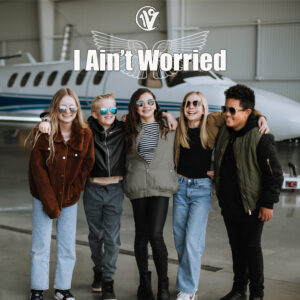 One Voice Children's Choir members pose in front of a plane wearing aviator glasses